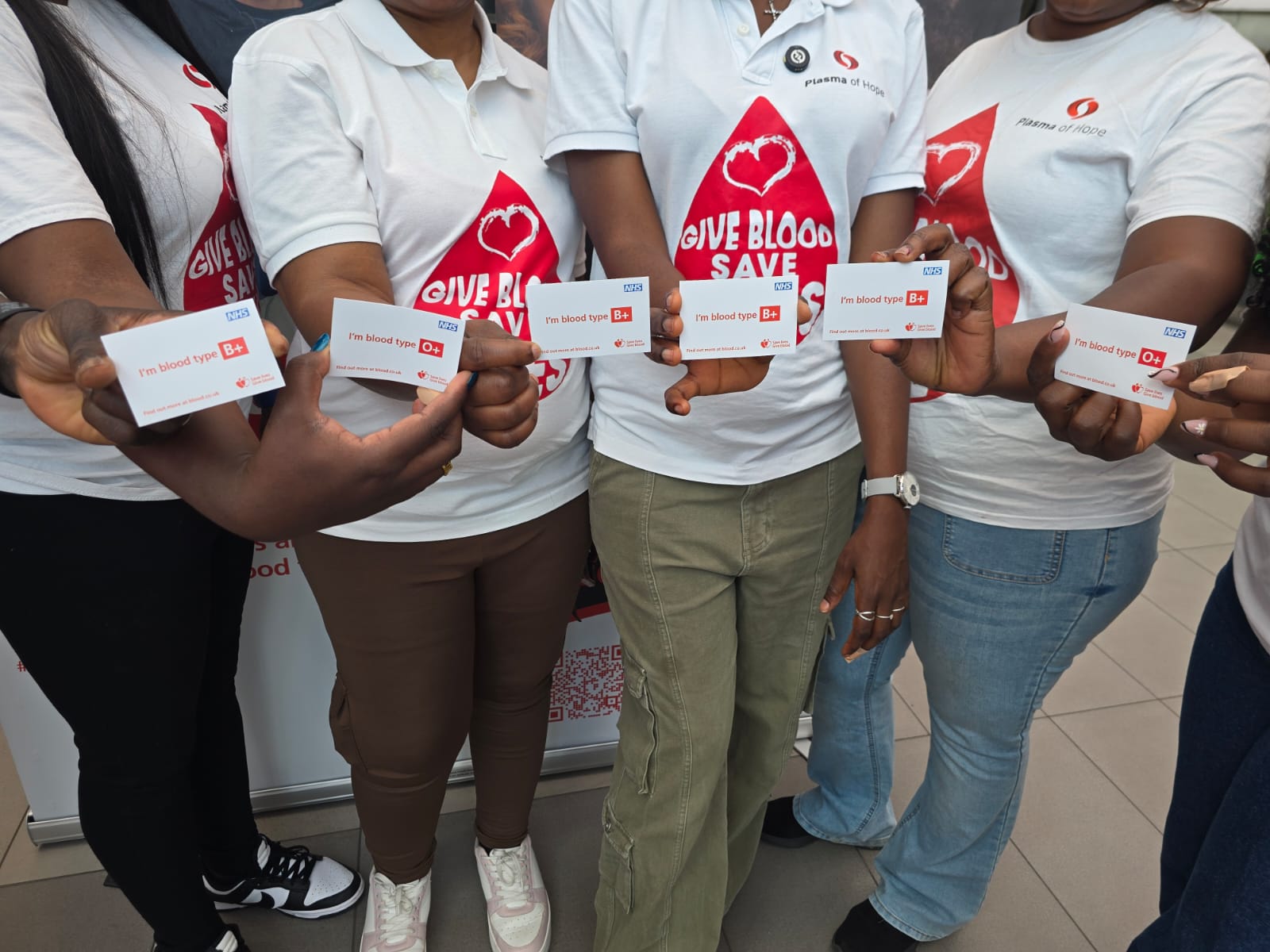 Plasma of Hope volunteers hold cards showing their blood types